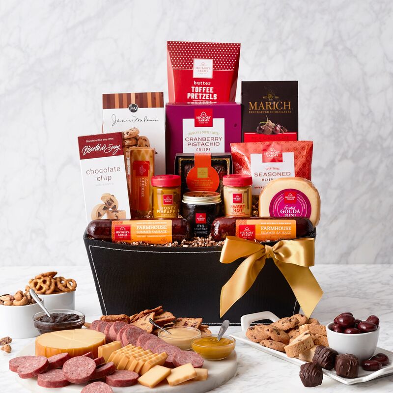 Classy black basket is filled with savory snacks and sweets and accented with a gold bow. Includes Parmesan Focaccia crackers, Chocolate chip cookies, Summer salami, Beef sausage, Vintage cheddar cheese round, Swiss cheese triangle, Pepper cheese triangle, Pimento stuffed olives, Smoked almonds, Cranberry medley trail mix, and a Cheese spreader