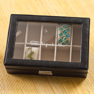 Women's Leather Jewelry Box $58.99 Black leather jewelry box with a glass hinged lid. Inside are 10 khaki suede-like velvet compartments with removable pillows.