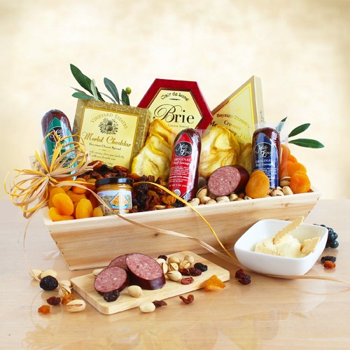 Handsome wooden gift tray with natural finish is filled with an assortment of sausages, cheeses, dried fruit and other snacks. 